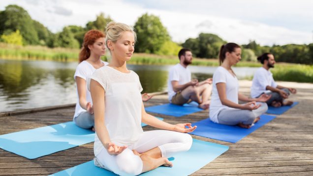 people meditating in yoga lotus pose outdoors